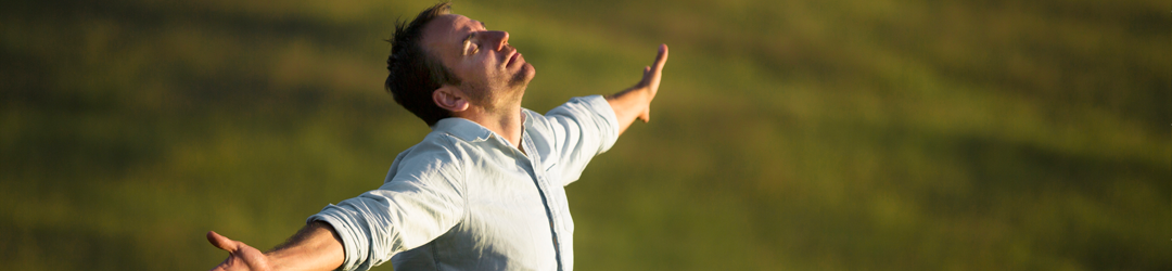 Man with outstretched arms looking into sun